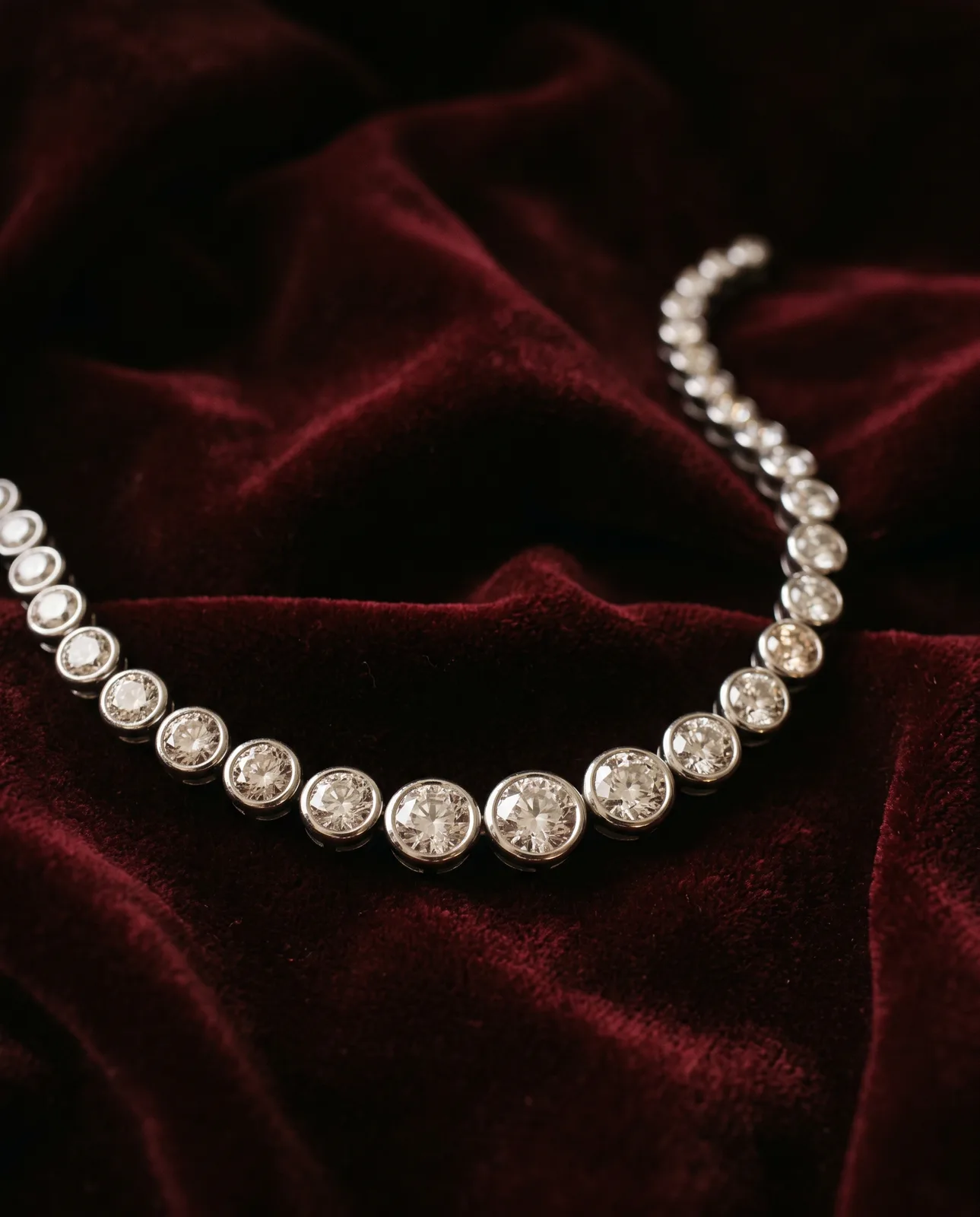 A rivière necklace of graduated diamonds in white gold on dark velvet