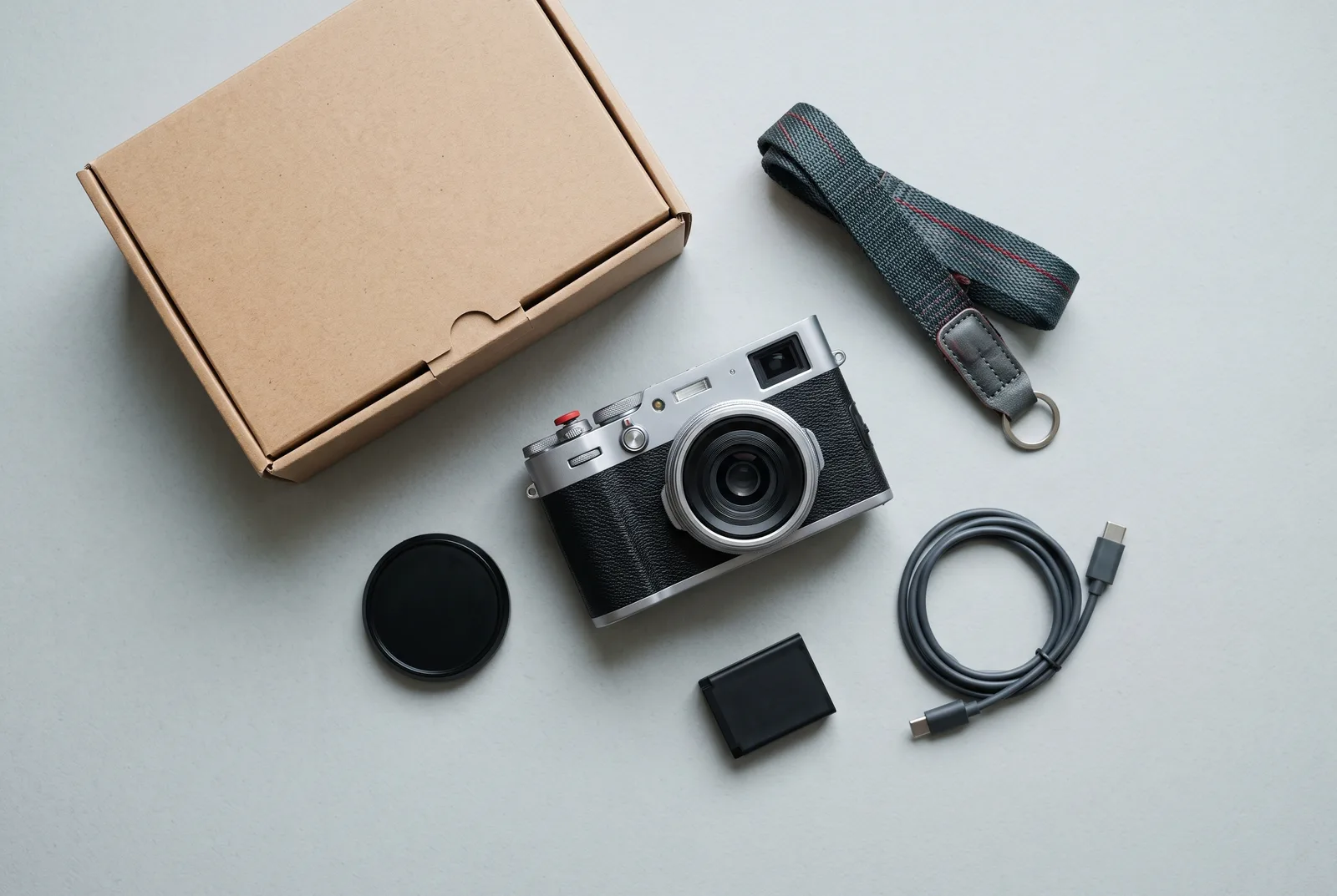 Field One camera laid out with its battery, strap, lens cap and cable
