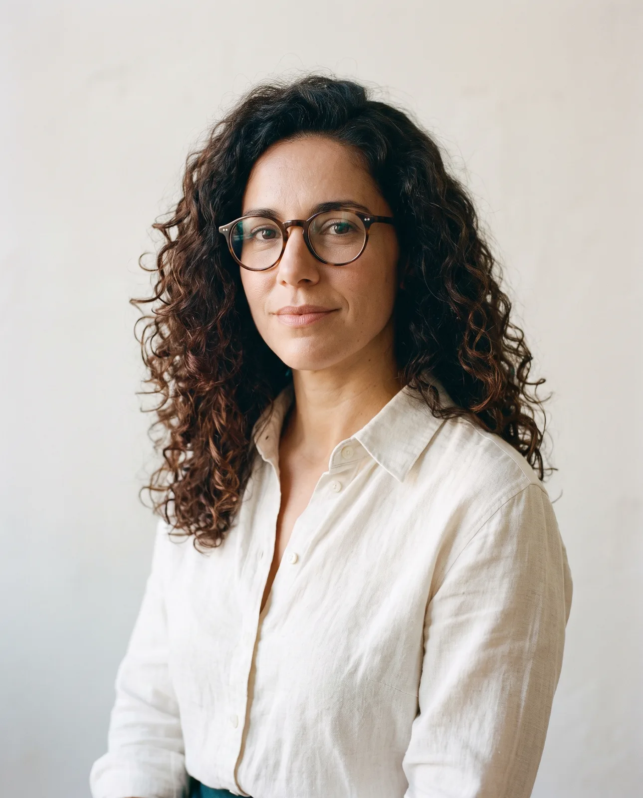 Portrait of Rania Khoury, a woman in her late thirties with dark curly hair and glasses