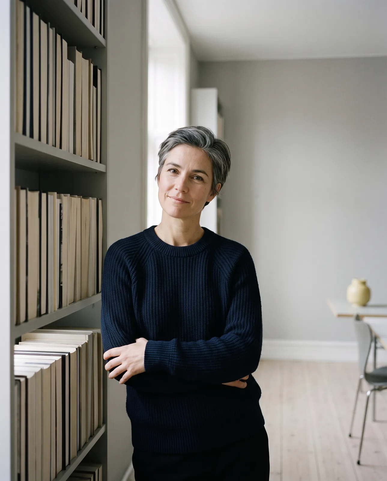 Lena Hart standing by a bookshelf in her Business Bay studio